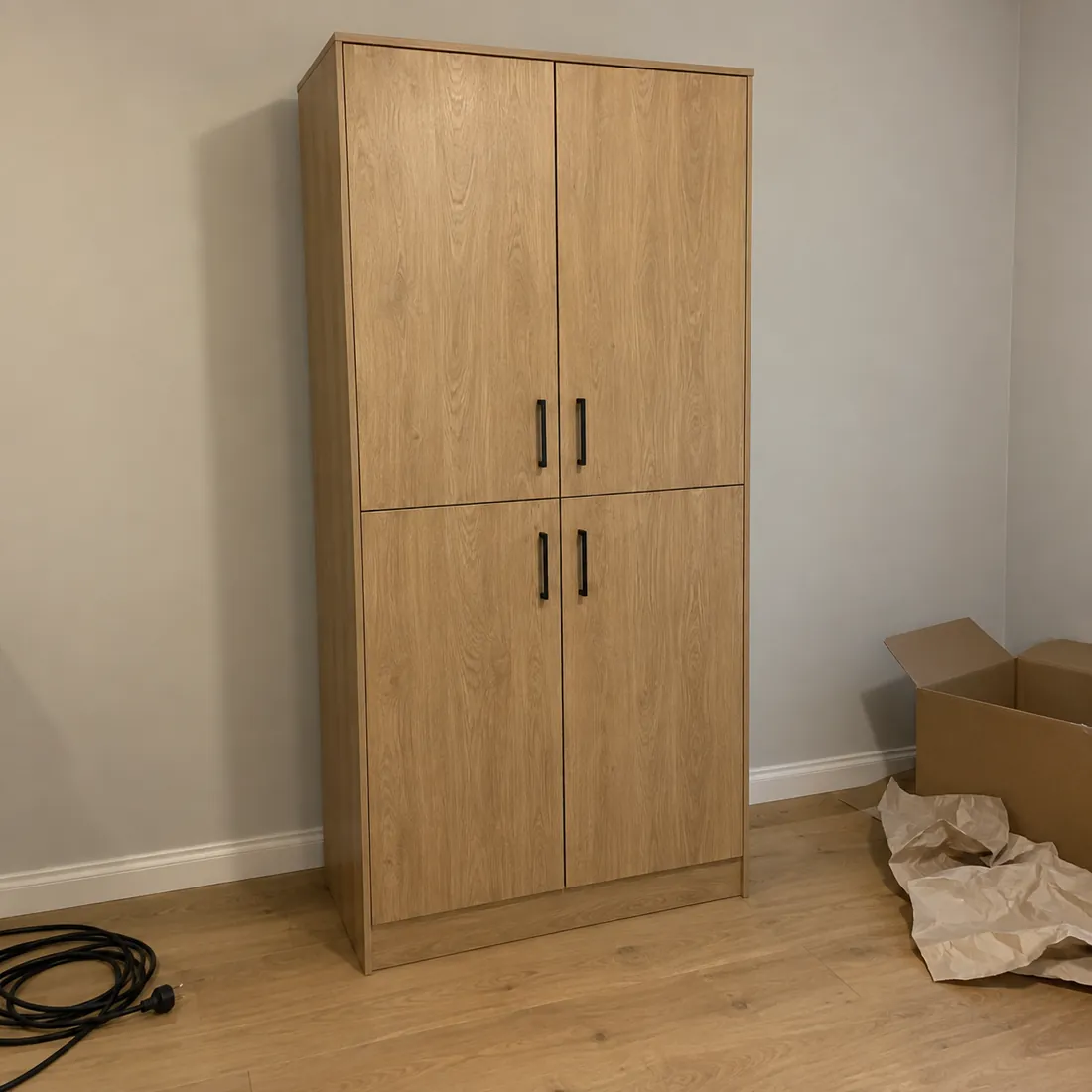 AI-generated starting image: an oak cabinet in uneven light, with a cable and packaging on the floor.
